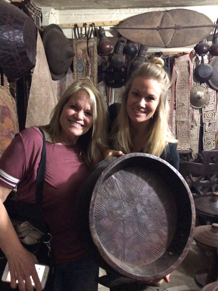 Diana and Bree holding a traditional serving to hold the large circular “injera” with different stews spooned around the flatbread—eaten with fingers!